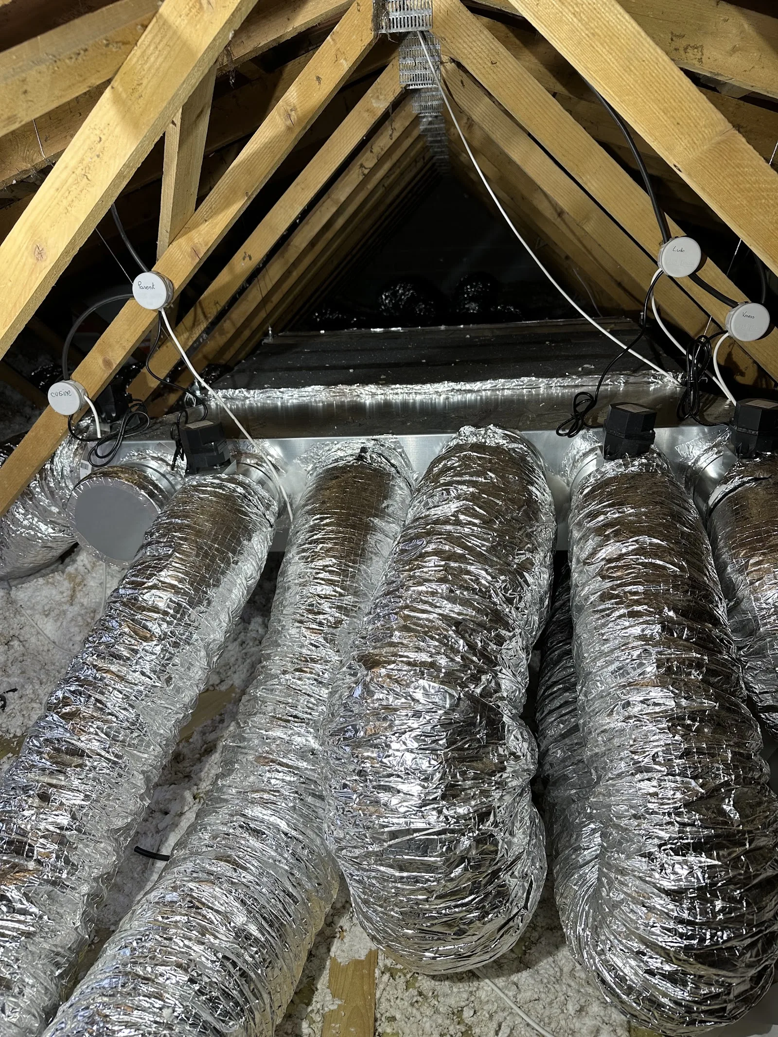 Gaines de climatisation étiquetées pièce par pièce dans des combles.
