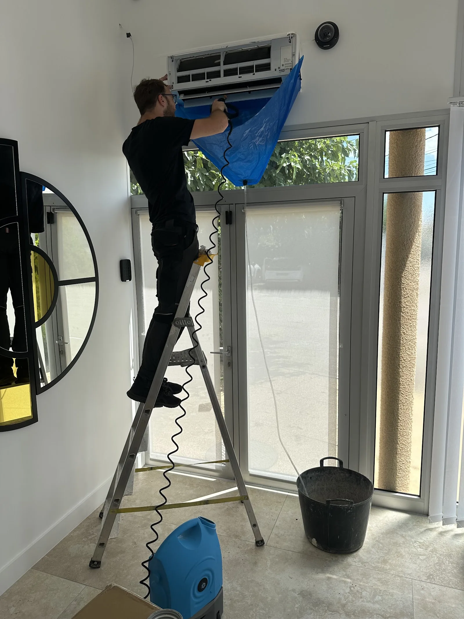 Intervention sur une climatisation murale, sur escabeau.